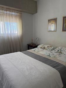 a bedroom with a large white bed and a window at Depto calle 51 in La Plata