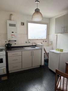 a kitchen with white cabinets and a sink and a window at Depto calle 51 in La Plata