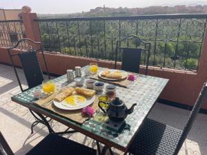 a table with breakfast food on a balcony at dar olivegarden inn in Aït Ouahi