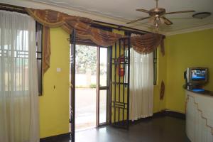 sala de estar con ventilador de techo y puertas correderas de cristal en Durban Motel Najjanankumbi Kampala, en Kampala
