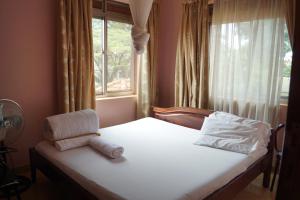 Dormitorio con cama con ventana y almohada en Durban Motel Najjanankumbi Kampala en Kampala