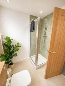 a bathroom with a shower and a toilet and a glass door at Golden Sands Escape Weymouth Entire House in Wyke Regis