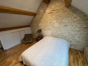 a bedroom with a bed and a stone wall at Le Verger de la Tannerie in Chesley