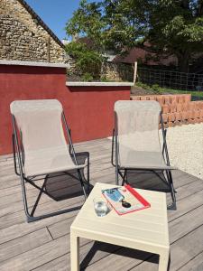 two chairs and a table and a book on a deck at Le Verger de la Tannerie in Chesley