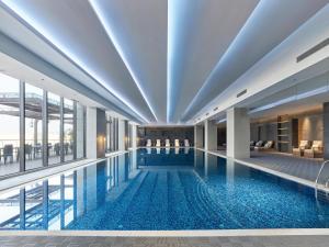 a large swimming pool in a building with windows at Doubletree By Hilton Quzhou in Quzhou