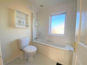 a bathroom with a toilet and a tub and a window at Dublin Cosy Home in Dublin