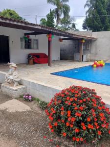 a house with a swimming pool and a plant with flowers at Sítio Araújo in Ibiúna
