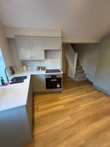 a kitchen with white cabinets and a sink and a staircase at Windsor Flat 90C in Windsor