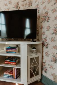 a television on a white entertainment center with books at Strassner Suites - Imy Suite in Hermann