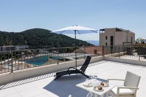 a balcony with a table and chairs and an umbrella at Villa Misita Elegant SeaView Rooms in Dubrovnik