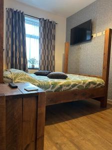 a bedroom with a wooden bed with a television on the wall at Snuggle Inn Burnley in Burnley