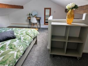 a bedroom with a bed and a table with a vase of flowers at Snuggle Inn Burnley in Burnley