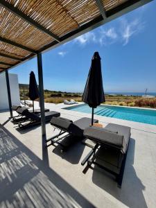a patio with chairs and umbrellas next to a swimming pool at Faragas Hill Harmony Villa in Angairiá