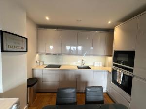 a kitchen with white cabinets and a sink and some stools at Stunning 2Bedrooms, 2Baths, Balcony, Parking in Colindale