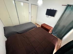 a small bedroom with two beds and a television at Duplex parque in Santiago del Estero