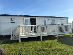 a white house with a porch and a deck at Shivvys at sandylands in Stevenston