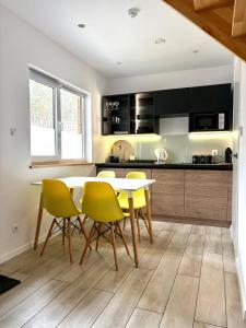 a kitchen with a table and yellow chairs at Amare Domki in Pobierowo