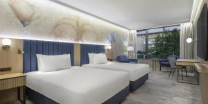 a hotel room with two beds and a desk at Doubletree By Hilton Plovdiv Center in Plovdiv +160 photos