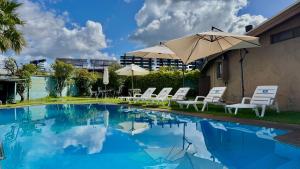 a swimming pool with white chairs and an umbrella at Hotel Econohotel in Los Ángeles
