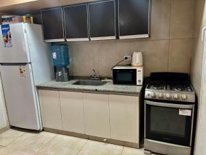 a kitchen with a sink and a stove and a microwave at Duplex DEL CARMEN in Santiago del Estero