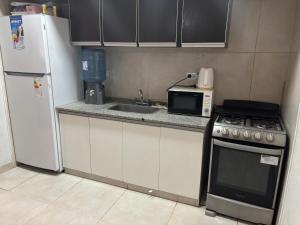 a kitchen with a microwave and a stove and refrigerator at Duplex DEL CARMEN in Santiago del Estero +4 photos