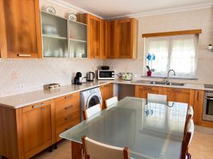 a kitchen with a glass table and wooden cabinets at Vivenda Godinho in Nazaré