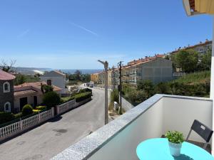 a table on a balcony with a view of a street at Vivenda Godinho in Nazaré