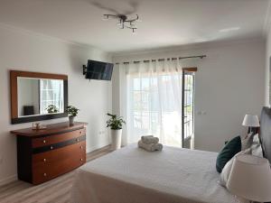 a bedroom with a bed with a dresser and a mirror at Vivenda Godinho in Nazaré