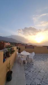 a table and chairs on a balcony with the sunset at LH Appart 1 bel appartement cosy, vu sur montagnes, proche du lac de Bin el Ouidane et de cascades d'Ouzoud in Afourer