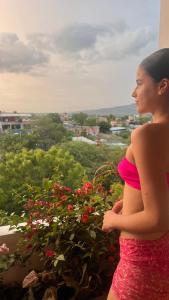 a pregnant woman in a pink bikini looking at flowers at Hospedaje SAUNA & SPA NOAH in Bagua Grande