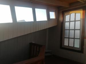 a room with three windows and a wooden bench at Habitación tu Refugio in Isla Negra