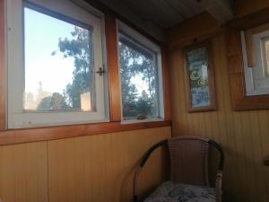 a chair in a room with two windows at Habitación tu Refugio in Isla Negra +2 photos