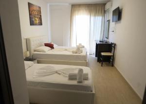 ein Hotelzimmer mit zwei Betten und einem Fenster in der Unterkunft Mare Blue Hotel Drymades in Dhërmi
