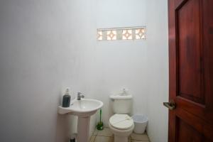 a white bathroom with a toilet and a sink at Casa Osú in Sámara