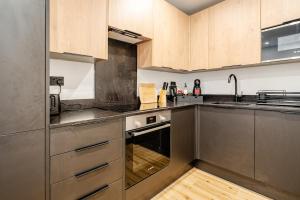 a kitchen with stainless steel appliances and wooden cabinets at Luxury Apartment Close to Elstree & Borehamwood Station in Borehamwood