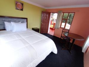 a bedroom with a large white bed and a table at Casa Amadeus in Estanciasuyo