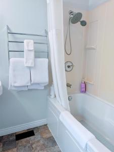 a white bathroom with a tub and a shower at Executive Suite 2 Bedroom Serviced Apartment in Alert Bay