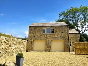 a stone house with two garage doors in a yard at 1 Bed in Colne oc-86513 in Rawdon