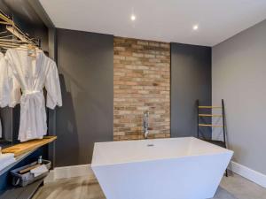 a large white bath tub in a room with a brick wall at 1 Bed in Colne oc-86513 in Rawdon +7 photos