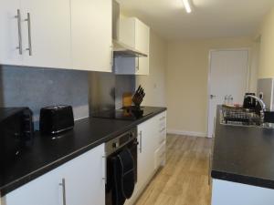a kitchen with white cabinets and a black counter top at Portman House in Middlesbrough