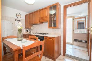 a kitchen with wooden cabinets and a table with a vase of flowers at Hedoné apartment in Schisò +31 photos