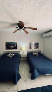 a bedroom with two beds and a ceiling fan at Mision del Sol 302 in Bahía Kino