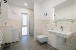a white bathroom with a sink and a toilet at Ferienwohnung Boddentraum in Zingst +8 photos