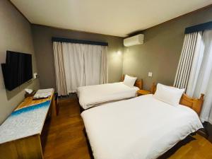 a hotel room with two beds and a television at Nikko Akarinoyado Villa Revage in Nikko