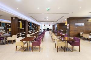 a restaurant with wooden tables and purple chairs at Hampton by Hilton Istanbul Kayasehir in Istanbul
