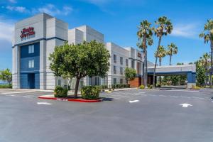 a building with a tree in a parking lot at Hampton Inn & Suites Lathrop in Lathrop