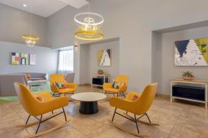 a waiting room with yellow chairs and a table at Spark by Hilton Tucson Reid Park in Tucson