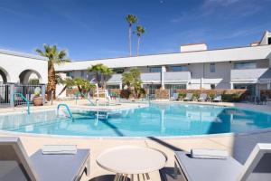 a large swimming pool with tables and chairs in front of a building at Spark by Hilton Tucson Reid Park in Tucson +59 photos