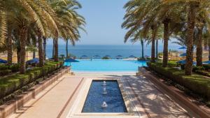 a pool with palm trees and the ocean in the background at Al Husn Hotel Muscat - managed by Hilton in Muscat +113 photos