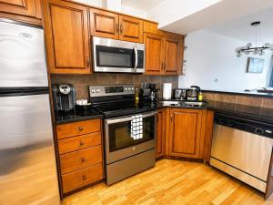 a kitchen with wooden cabinets and stainless steel appliances at Alpine Hideaway at Alpine Village in Canmore